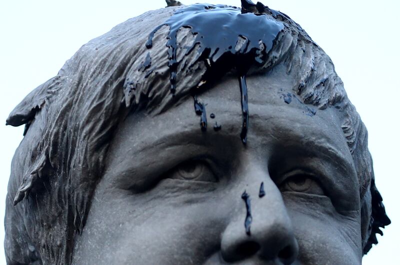 Oil thrown by Greenpeace demonstrators in an act of symbolism drips down the face of the Boris Johnson statue. Reuters