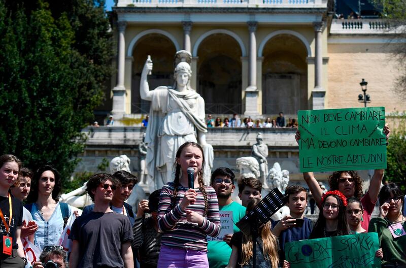 16-year-old Swedish climate change activist, Greta Thunberg (C) speaks during the Fridays For Future rally in Piazza del Popolo in Rome on April 19, 2019.
 Thunberg rose to international prominence last August for organising the first 'School strike for climate', also known as Fridays For Future, a global movement of school students who swap classes for demonstrations to demand action to prevent further global warming and climate change. The placard (R) reads "It's not the climate that has to change but our habits". / AFP / Filippo MONTEFORTE
