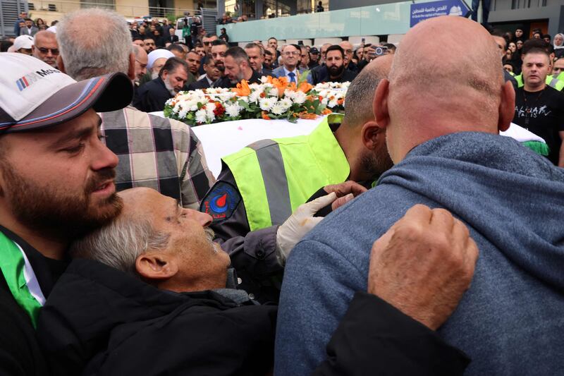 The father of cameraman Rabih Maamari faints during his son's funeral. AFP
