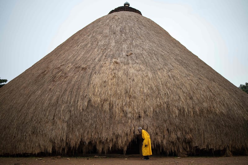 (FILES) A traditional guard stands in front of one of the buildings belonging to the Kasubi Royal Tombs in Kampala, Uganda on June 13, 2023.  The World Heritage Committee, meeting in Riyadh until September 25, 2023 decided on September 12, 2023 to remove the Kasubi Royal Tombs from the List of World Heritage in Danger following the restoration work carried out successfully by Uganda in coordination with UNESCO.  (Photo by Stuart Tibaweswa  /  AFP)