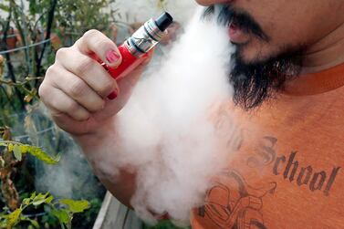 A man blows a puff of smoke as he vapes with an electronic cigarette. AP Photo / Jim Mone