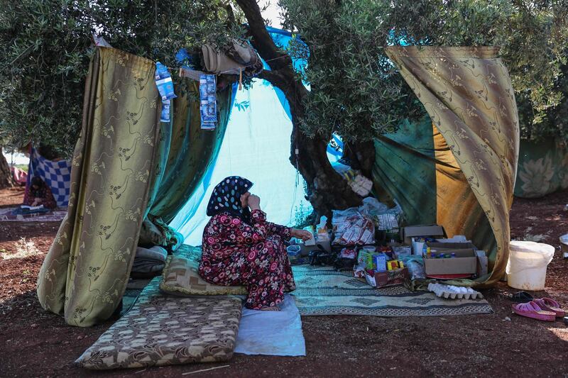 A displaced Syrian woman sits under the shade of a tree in the village of Atme, in the rebel-held northern Idlib province.   AFP