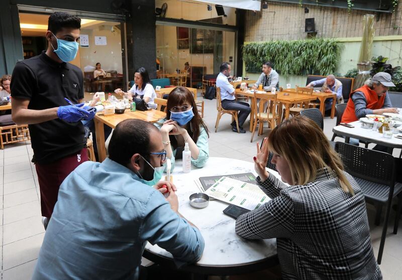 A waiter takes an order at an outdoor terrace of a restaurant as Lebanon eases its coronavirus lockdown, and its restaurants struggle to choose between opening with reduced capacity or staying shut, amid an unprecedented economic crisis that has slashed profit and raised cost, in Beirut. Reuters