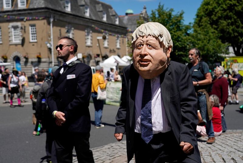 An activist wears a giant head depicting British Prime Minister Boris Johnson as he marches through the streets during a demonstration around the meeting of the G7 in Falmouth, Cornwall, England, Saturday, June 12, 2021. Leaders of the G7 gather for a second day of meetings on Saturday, in which they will discuss COVID-19, climate, foreign policy and the economy. (AP Photo/Alberto Pezzali)