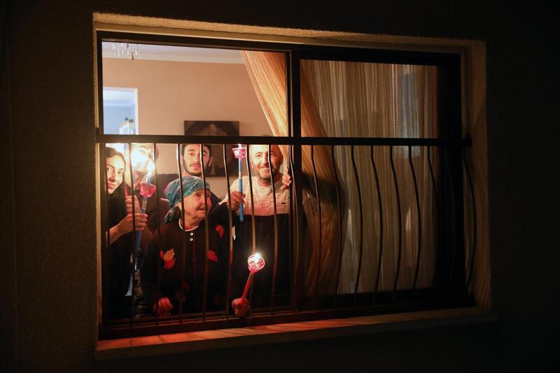 CYPRUS: A family hold lighten candles symbolizing the Holy Light at the window of their apartment, as people are not allowed to attend the Orthodox Easter midnight mass, in Nicosia, on April 19, 2020. EPA
