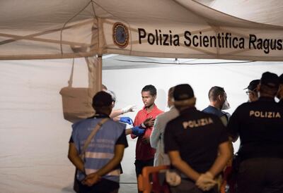 Police check a migrant disembarked from Frontex ship "Protector" at the port of Pozzallo, Sicily, Italy, in the early hours of Monday, July 16, 2018. Migrants aboard two border patrol ships have disembarked in a Sicilian port after a half-dozen European countries promised to take some of them in rather than have Italy process their asylum claims alone.(Francesco Ruta/ANSA via AP)