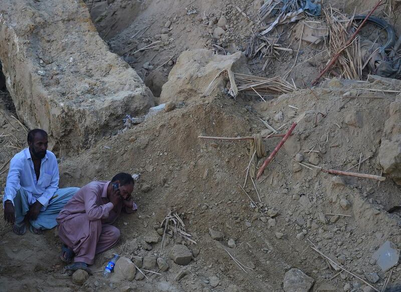 A Pakistani mourner talks on a mobile phone at the site of a landslide in Karachi. Asif Hassan / AFP