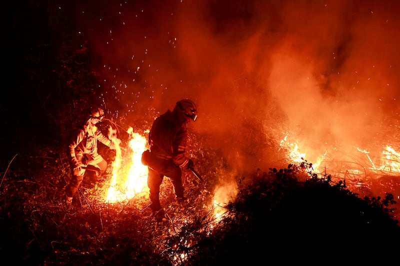 Firefighters tackle flames in a forest as the heat and a prolonged drought caused wildfires in Asturias, Spain. Reuters