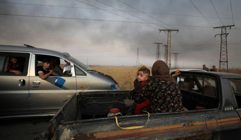 A woman with a baby sits at a back of a truck as they flee Ras Al Ain town, Syria. Reuters