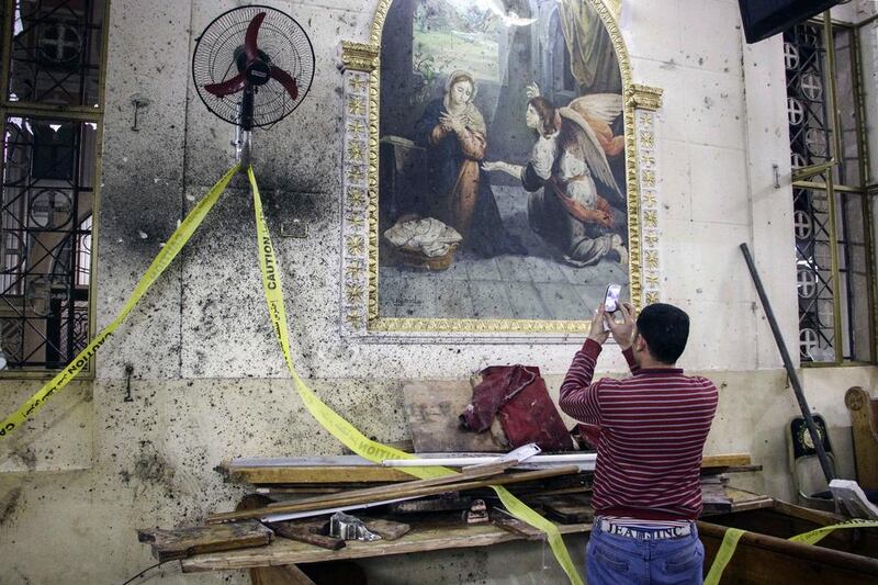 A man takes pictures of the destruction, debris and bloodstains on the walls inside the Mar Girgis Coptic Orthodox Church in the Nile Delta City of Tanta, north of Cairo. AFP