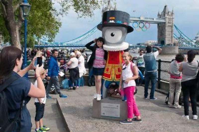 Tourists pose for pictures beside a model of the 2012 Olympic mascot, Mandeville, near London's Tower Bridge.