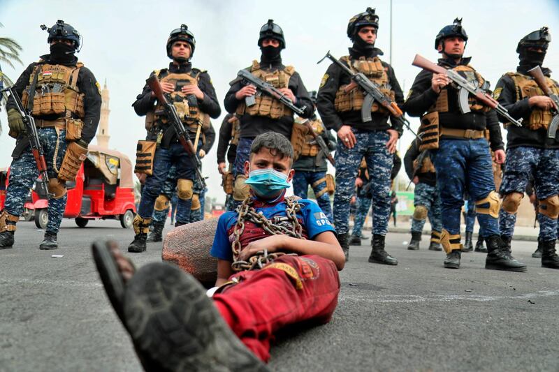 Anti-government protesters stage a sit-in while security forces stand guard during ongoing protests in downtown Baghdad, Iraq. AP Photo