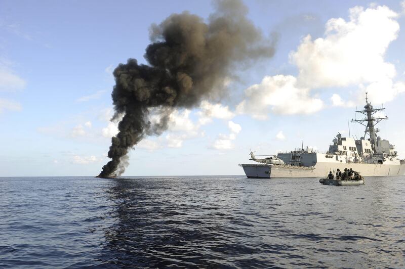 In this handout picture released by the US Navy, the Arleigh Burke-class guided missile destroyer USS Farragut (DDG 99) passes by the smoke from a suspected pirate skiff it had just disabled. Courtesy: Cassandra Thompson / US Navy