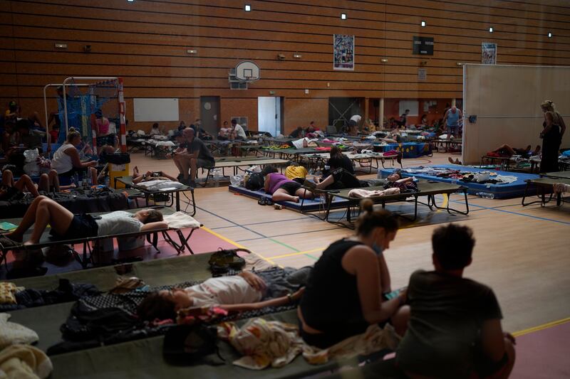 People rest in a gym in Bormes-les-Mimosas after their campsite was evacuated with the flames closing in.