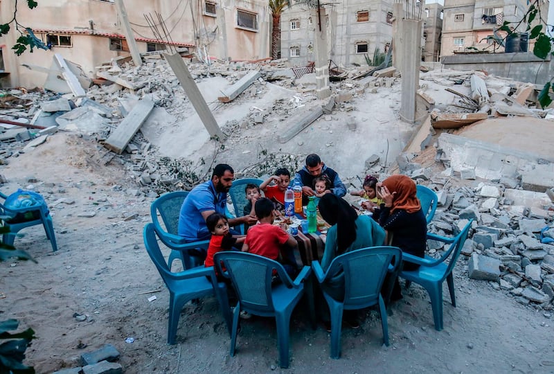 A Palestinian family break their fast next to their house that was destroyed during an escalation with Israel, in Rafah the southern Gaza Strip, 8 May.  AFP