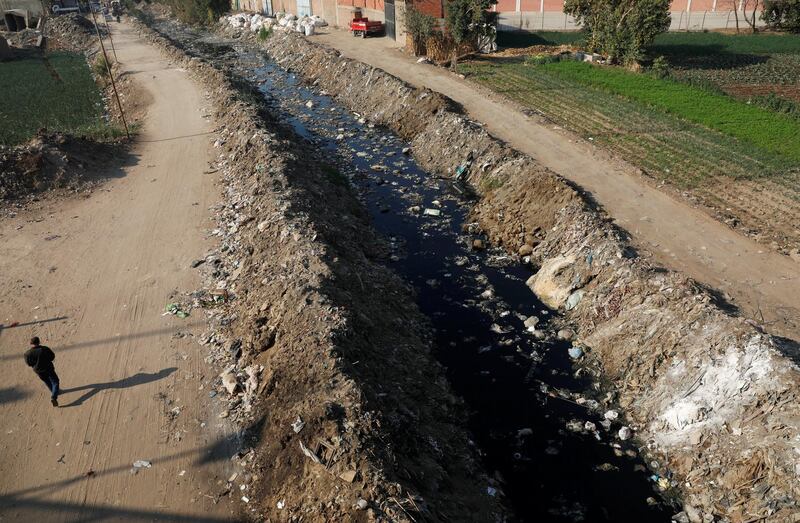 A man walks beside a water canal filled with garbage around agricultural land on the outskirts of Cairo, Egypt. Reuters