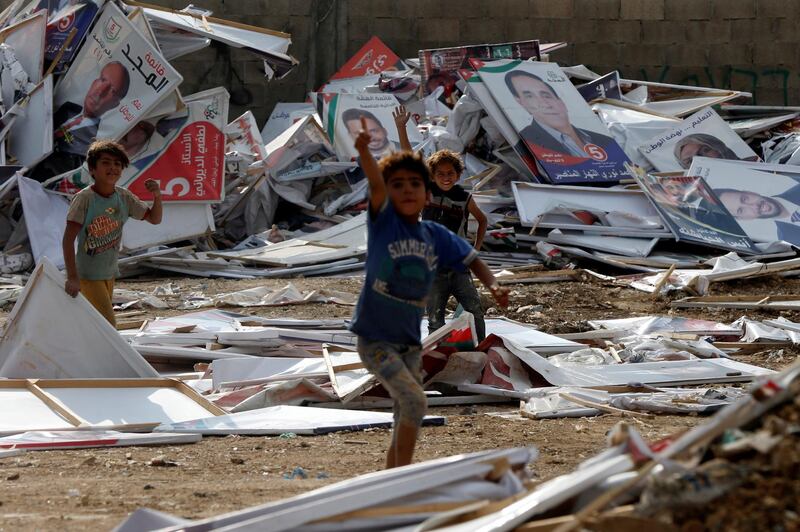 Children gesture as they collect wood from parliamentary candidates' posters, which were removed by the municipality after the results of the parliament elections were announced in Amman, Jordan. Reuters