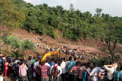 People watch army soldiers and rescue workers recover bodies of landslide victims even as they try to pull out two buses that were covered in mud after a landslide triggered by heavy monsoon rain in Urla village, Himachal Pradesh state, India, Sunday, Aug. 13, 2017. The landslide that occurred early Sunday buried part of a highway, trapping two buses and at least three cars. (AP Photo/Shailesh Bhatnagar)