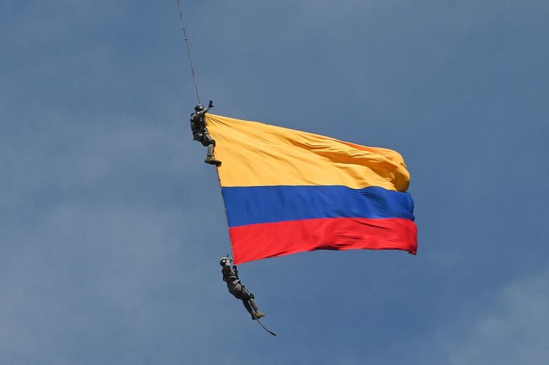 Air Force members Jesus Mosquera and Sebastian Gamboa hang from an helicopter as they wave a Colombian flag as part of a performance during the Flower Festival in Medellin, Colombia, on August 11, 2019. According to the Colombian Air Force, Mosquera and Gamboa accidentally died after falling down when they were still hanging from the aircraft before landing at a local airport. / AFP / JOAQUIN SARMIENTO
