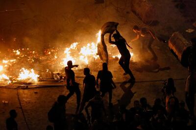 A man throws a mattress on a barricade as he tries to extinguish the fire set by anti-government protesters during ongoing demonstrations in Beirut, Lebanon, Wednesday, Nov. 13, 2019. Lebanese protesters said they will remain in the streets despite the president's appeal for them to go home