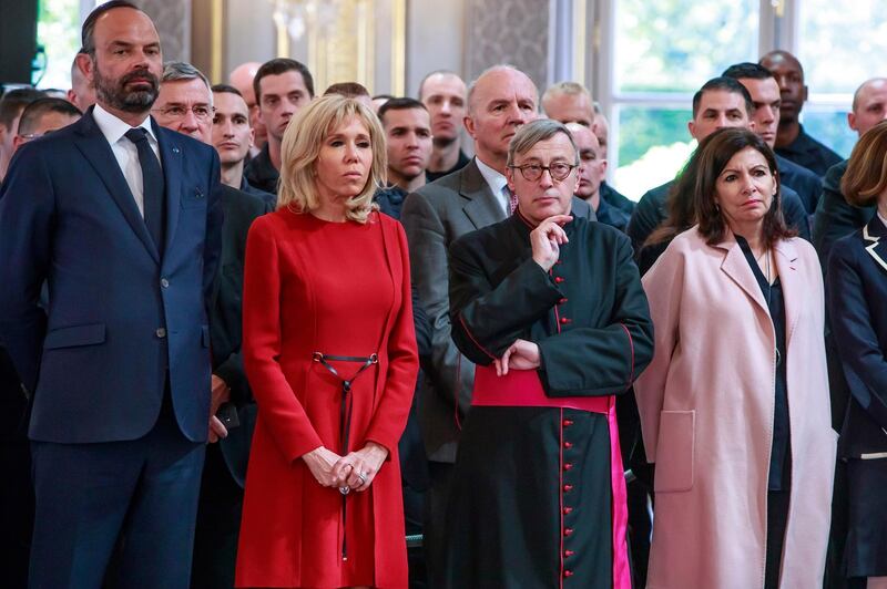 French Prime Minister Edouard Philippe, left, French President 's wife Brigitte Macron, second left, Archibishop of Paris Jean-Marc Chauvet and Paris mayor Anne Hidalgo listen to French President Emmanuel Macron addressing Paris Firefighters' brigade and security forces who took part at the fire extinguishing operations of the Notre Dame of Paris Cathedral fire, at the Elysee Palace in Paris, Thursday, April 18, 2019. France paid a daylong tribute Thursday to the Paris firefighters who saved the internationally revered Notre Dame Cathedral from collapse and rescued many of its treasures. AP