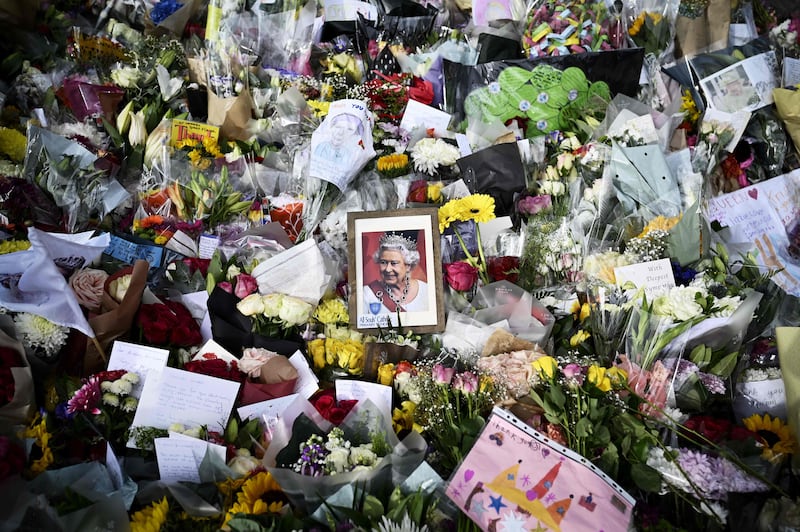 A picture of Queen Elizabeth is among flowers left by mourners outside Buckingham Palace in London. AFP