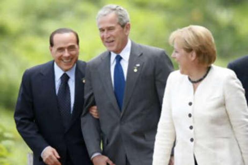 The Italian prime minister Silvio Berlusconi holds on to the arm of President George Bush as the German chancellor Angela Merkel looks on before posing for the official photo at the G8 summit today.