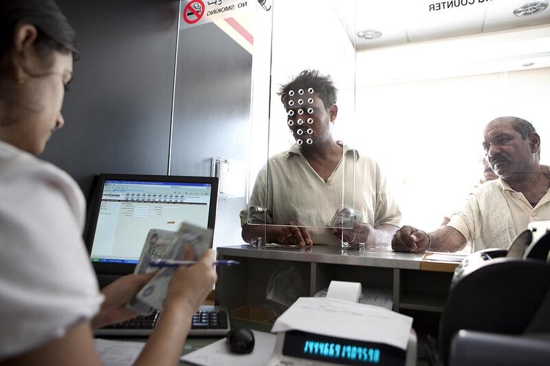 Cashier Rashmi D’Souza helps customers exchange money at a UAE Exchange branch on Hamdan Street in Abu Dhabi. Silvia Razgova / The National