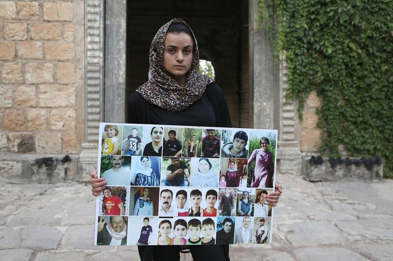Yazidi woman Ashwaq Haji, allegedly used by the Islamic State group (IS) as a sex slave, holds portraits of jihadists' victims from her village of Kocho near Sinjar, as she visits the Lalish temple, in Lalish, northern Iraq, on August 15, 2018. - A young Yazidi woman who fled to Germany but returned home to northern Iraq says she cannot escape her Islamic State group captor who held her as a sex slave for three months. 
Ashwaq Haji, 19, says she ran into the man in a German supermarket in February. Traumatised by the encounter, she returned to Iraq the next month. Like many other Yazidis, she was kidnapped by IS when the jihadists seized swathes of Iraq in the summer of 2014. (Photo by - / AFP)