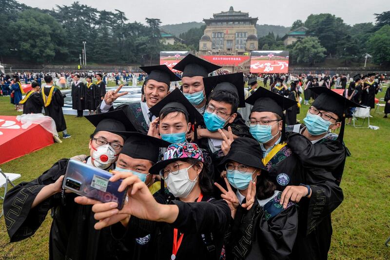 University graduates wearing face masks take a selfie during their graduation ceremony at Wuhan University in China's central Hubei province.  AFP