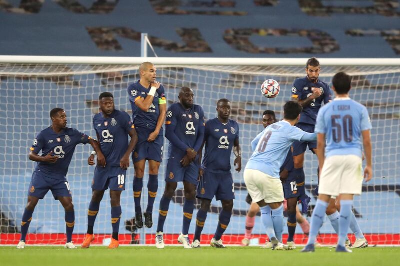 Manchester City's German midfielder Ilkay Gundogan (CR) scores their second goal from a free kick during the UEFA Champions League football Group C match between Manchester City and Porto at the Etihad Stadium in Manchester, north west England on October 21, 2020. (Photo by Martin Rickett / POOL / AFP)