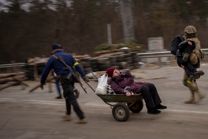 A Ukrainian soldier and a militia man help a fleeing family on the outskirts of Kyiv, Ukraine, on March 5, 2022. AP Photo