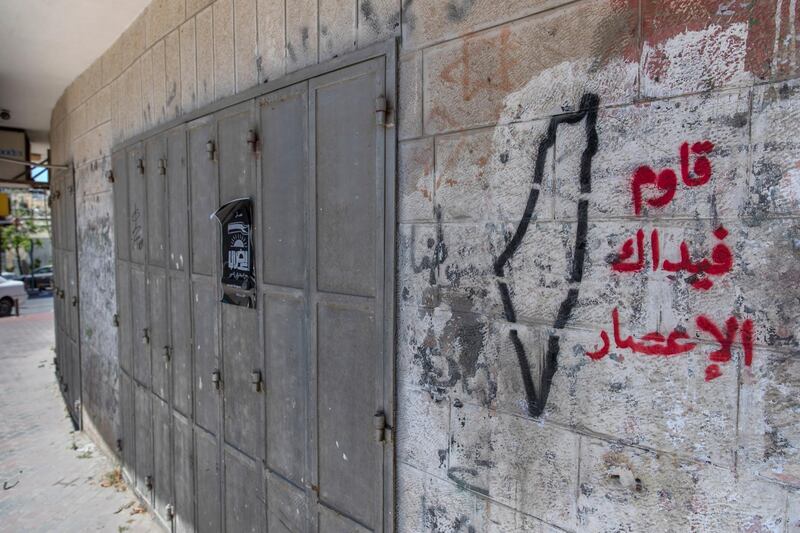 Graffiti in Arabic on the wall of a closed shop reads "resist. Your hands are the hurricane,"  during a general strike, in the West Bank city of Ramallah. AP Photo