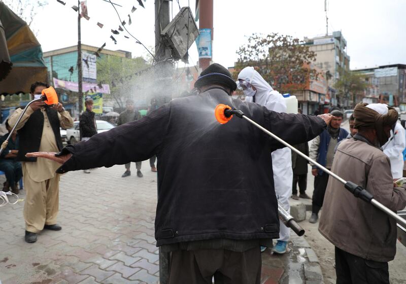 Afghan National Procurement Authority workers spray disinfectant on a man in Kabul, Afghanistan. Reuters