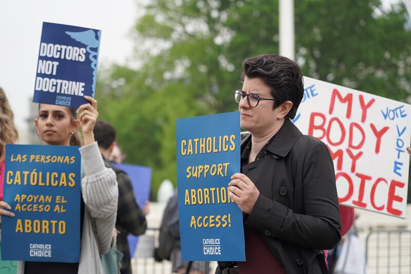 A woman holds a sign that reads: Catholics support abortion access in front of the Supreme Court. Willy Lowry / The National