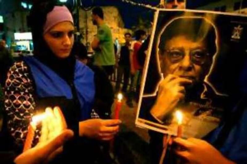 Palestinians hold candles in front of a portrait of late Palestinian poet Mahmud Darwish during a candle-lit vigil in the West Bank city of Nablus on August 12, 2008. Thousands of Palestinians are expected to attend tomorrow the funeral for their "national" poet Mahmud Darwish, whose writings captured the spirit of the Palestinian struggle. Darwish, who died on August 9, 2008 at the age of 67 in a US hospital from complications following open-heart surgery, will be buried near the Cultural Palace in the West Bank city of Ramallah, Palestinian Authority officials said. AFP PHOTO/JAAFAR ASHTIYEH