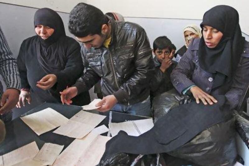 A worker inspects the list of names registered to receive new and second-hand clothes as part of humanitarian aid in Aleppo last week. A multi-million dollar aid programme for Syria, funded by the UN and implemented in association with the Syrian government, has drawn heavy criticism from the opposition. Muzaffar Salman / Reuters