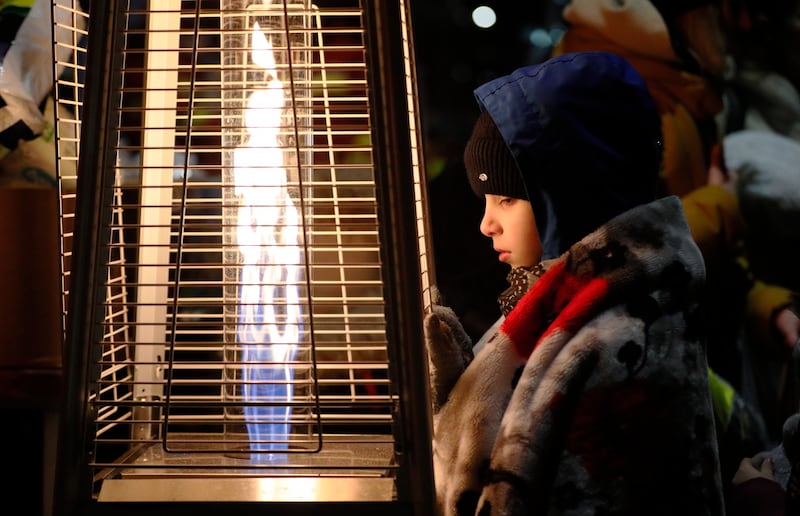 A Ukrainian refugee boy, wearing a blanket on his shoulders, warms his hands with a gas heater shortly after crossing the Siret border into northern Romania. EPA