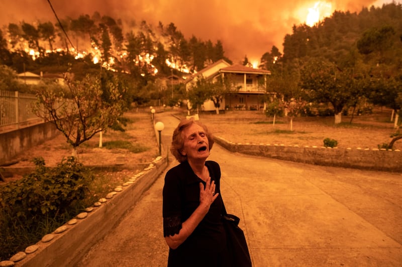 An elderly resident reacts with anguish as fire approaches her home in the village of Gouves, on the island of Evia, Greece.  Thousands of residents were evacuated from Evia after wildfires hit Greece’s second biggest island.
