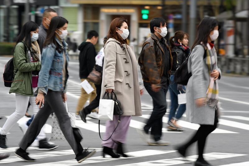 Pedestrians wearing protective masks cross an road in the Ginza area in Tokyo, Japan, on Saturday, Feb. 15, 2020. Japan's economy likely suffered its biggest contraction since 2014 at the end of last year leaving it in a vulnerable state, as fallout from China's viral outbreak threatens to turn a one-quarter-slump into a recession. Photographer: Akio Kon/Bloomberg