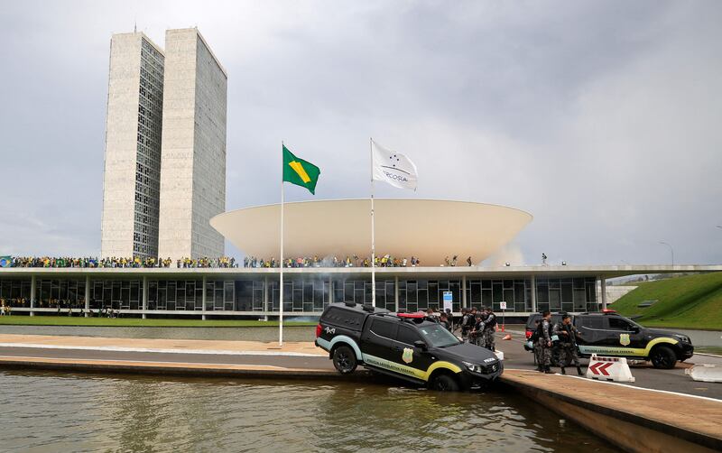 A police vehicle crashes into a fountain as Bolsonaro supporters invade the National Congress building. AFP