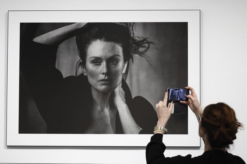 MOSCOW, RUSSIA - MARCH 16, 2017: A woman takes a picture of a photograph of actress Julianne Moore taken for the 2017 Pirelli Calendar on display at an exhibition titled "Pirelli Calendar 2017 by Peter Lindbergh" at Moscow's Multimedia Art Museum. The exhibition is open from March 17 to May 14, 2017. Artyom Geodakyan/TASS (Photo by Artyom Geodakyan\TASS via Getty Images)