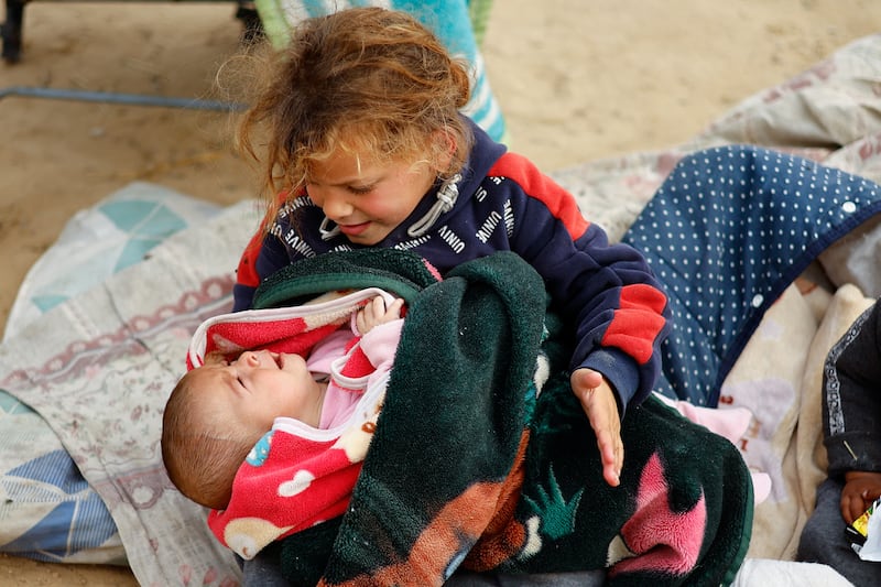 A displaced Palestinian child holds a crying baby in a camp in Rafah, in the southern Gaza Strip. Reuters
