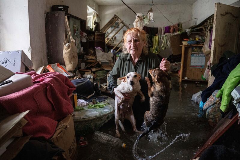 Tetiana with her pets, Tsatsa and Chunya, in her house that was flooded when the Kakhovka dam in Kherson was breached