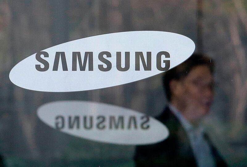 FILE - In this April 6, 2018 file photo, An employee walks past logos of the Samsung Electronics Co. at its office in Seoul, South Korea. Samsung Electronics said Thursday, April 26, 2018 its first-quarter earnings jumped 52 percent over a year earlier thanks to its mainstay memory chips that posted another record-high quarterly profit. (AP Photo/Ahn Young-joon, File)