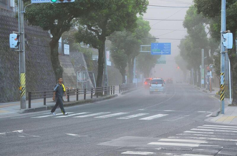 In this Sunday, Aug. 18, 2013 photo, a boy with a towel on his shoulder crosses a street covered by ash after the Sakurajima volcano erupted earlier in the day in Kagoshima, on the southern Japanese main island of Kyushu. People in the city wore masks and raincoats and used umbrellas to shield themselves from the ash after the erupton. (AP Photo/Kyodo News) JAPAN OUT, MANDATORY CREDIT *** Local Caption ***  Japan Volcano.JPEG-02e48.jpg