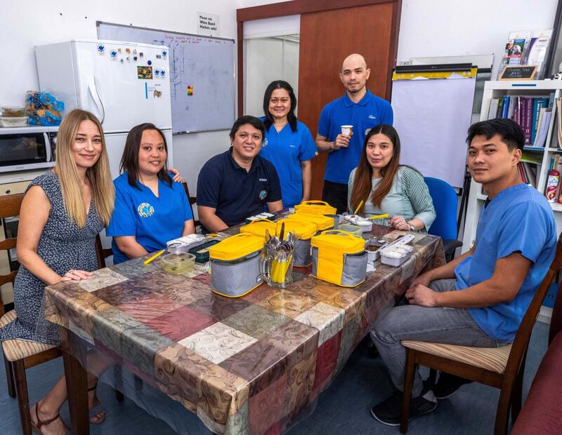 Abu Dhabi, U.A.E., August 28,, 2018. 
 British Veterinary Centre's Filipino staff were ordering their lunch each day from the same restaurant, the Khalidyah branch of Royal Pinoy but they got fed up of all the plastic waste.  So the admin manager, Jennifer Hale, ordered reusable lunch kits which the restaurant now refills each day for them. --- (L) Jennifer Hale with her Filipino Staff during lunch break.
Victor Besa/The National
Section:  NA