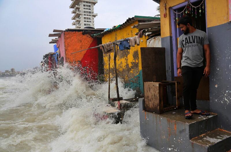 An Indian man stands near his house as waves caused by high tide hits the huts on the shore of the Arabian Sea in Mumbai, India, Wednesday, July 3, 2019. Heavy monsoon rains in Maharashtra have led to more than 30 deaths since Monday night, from collapsed walls, drownings and other causes. Dozens of others have been injured. (AP Photo/Rafiq Maqbool)