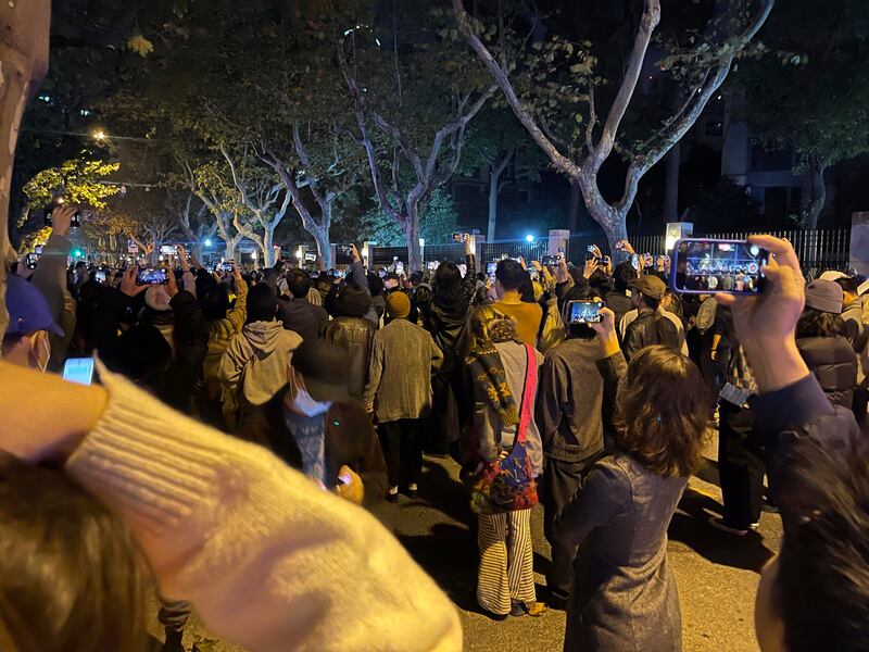 People record the scene as they mourn for the victims of a fire at a residential building in Urumqi city in China's Xinjiang region. Some say those killed were locked in at the time due to official Covid restrictions. Reuters