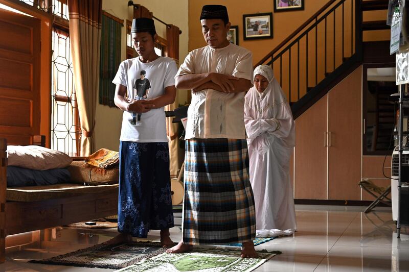 This picture taken on March 23, 2020 shows Bambang Soetono (C) and his relatives taking part in noon Islamic prayers at his home in Tangerang, after the government called on Muslims to avoid religious gatherings and practise social distancing as a preventive measure against the spread of the COVID-19 novel coronavirus. / AFP / Adek BERRY
